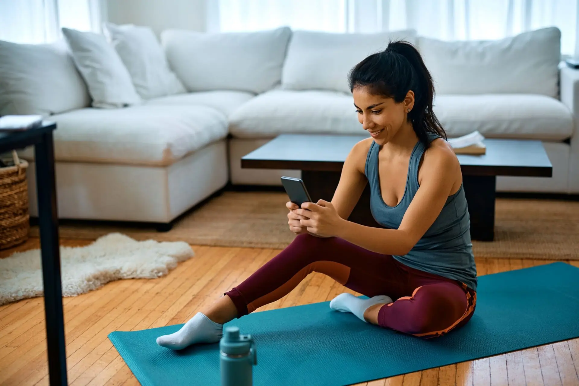 woman on a yoga mat on her phone
