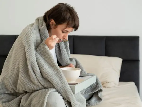 woman at home sick eating soup