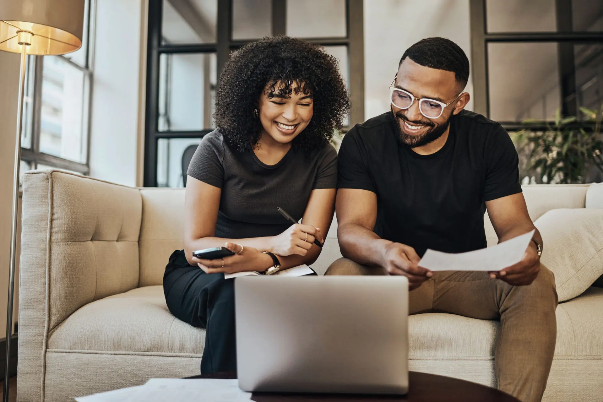 Woman and man in glasses on couch in front of laptop