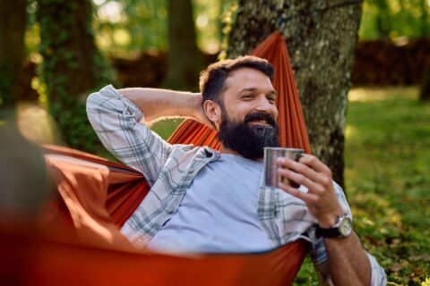 Man relaxing in hammock with coffee