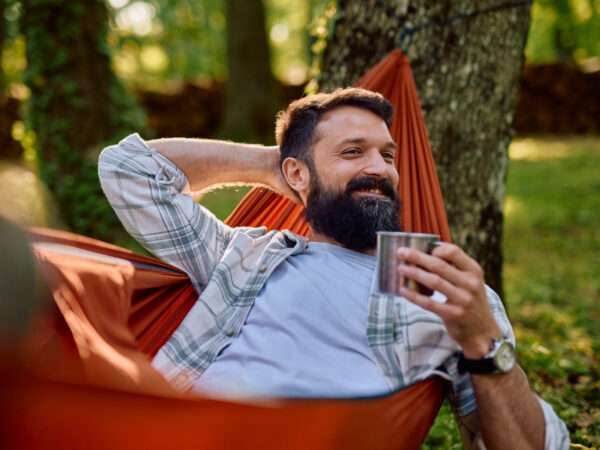 Man relaxing in hammock with coffee