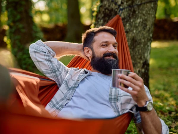 Man relaxing in hammock with coffee