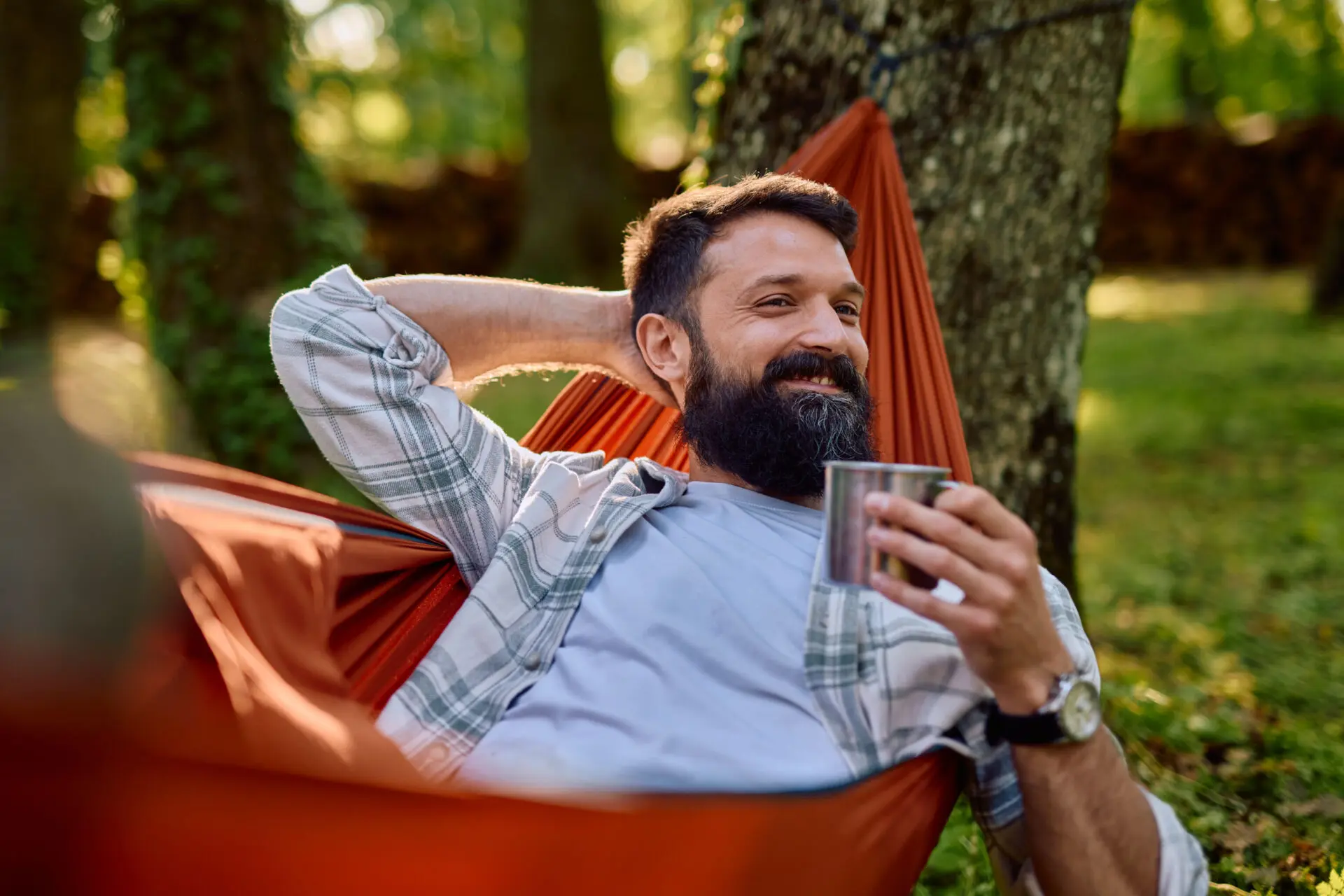 Man relaxing in hammock with coffee